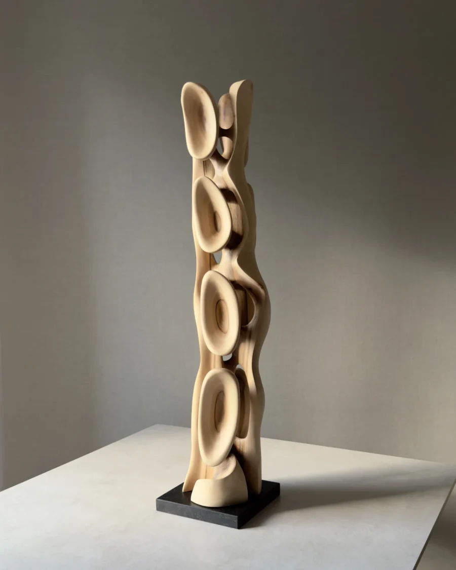 Side view of Ivory Flow revealing the flowing silhouette and open structure of the hand-carved walnut sculpture.