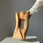 Lumen pear wood sculptural vase illuminated by warm natural light with soft shadows passing through the opening.