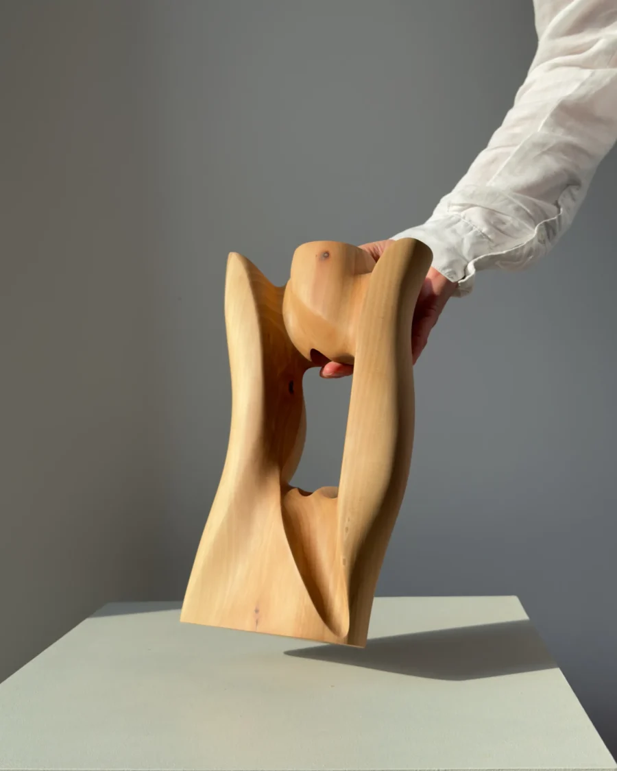 Lumen pear wood sculptural vase illuminated by warm natural light with soft shadows passing through the opening.