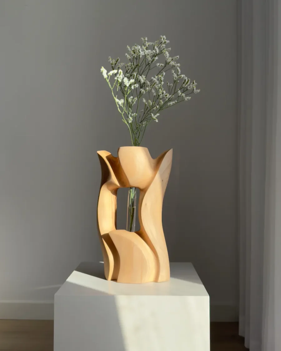 Lumen hand-carved pear wood sculptural vase with delicate white flowers in warm natural light.
