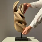 Silent Ascent walnut wood sculpture shown with a hand for size reference.