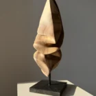 Silent Ascent one-of-a-kind walnut wood sculpture photographed in natural light on a black granite base.