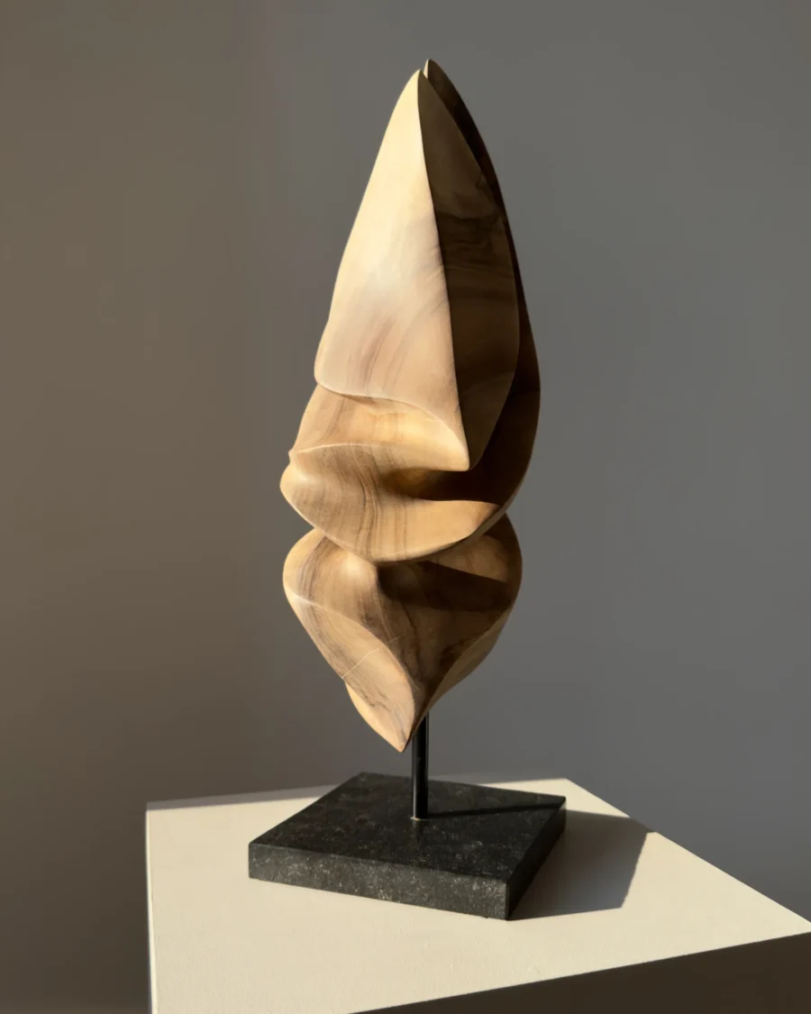 Silent Ascent one-of-a-kind walnut wood sculpture photographed in natural light on a black granite base.