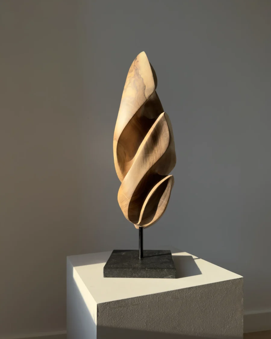Detail of the polished black granite base supporting the Silent Ascent walnut sculpture.