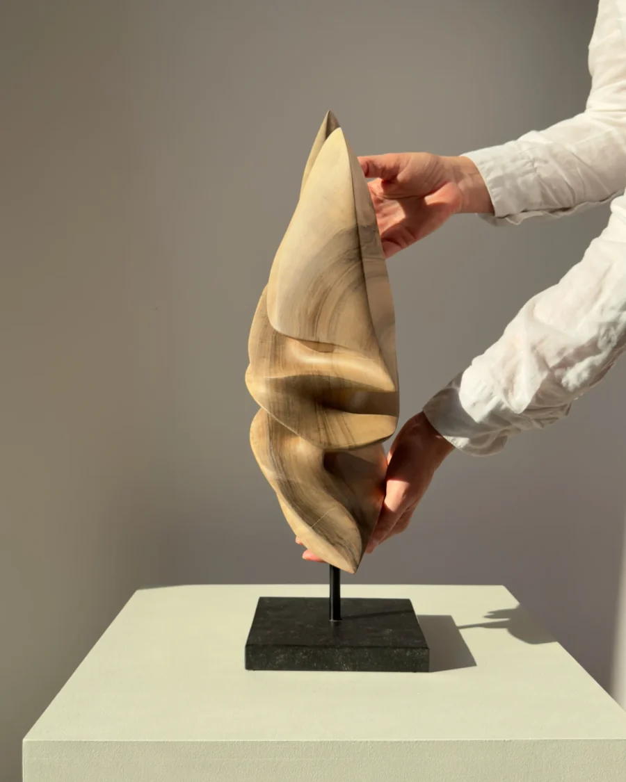 Hand-carved walnut wood sculpture Silent Ascent on a polished black granite base, front view.