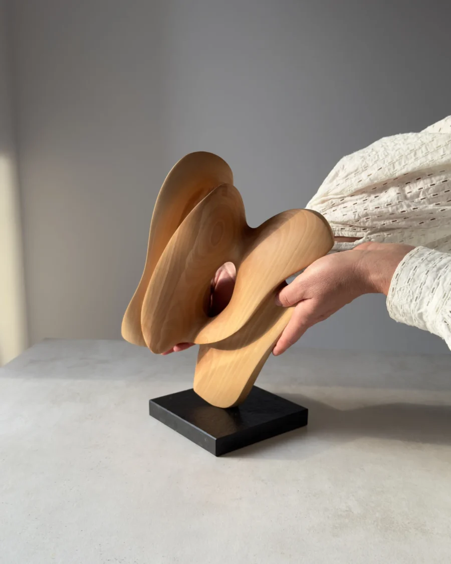 Hand-carved apple wood sculpture "Sway" shown in scale, mounted on a black granite base, rear view.