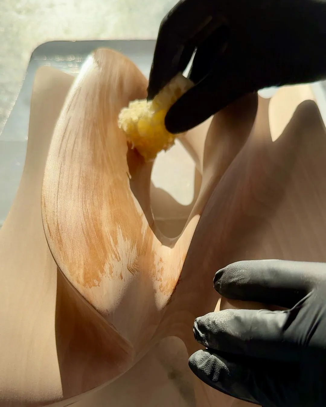 Applying natural hardwax oil to the finished Sway sculpture, revealing the warmth and grain of the apple wood.
