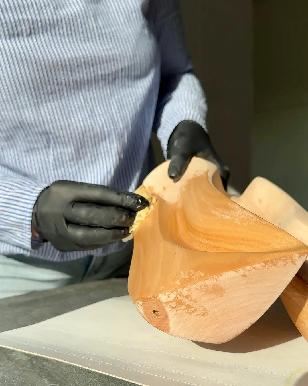 Hand finishing the smooth surface of the Sway sculpture with natural hardwax oil.