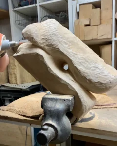 Hand carving the evolving form of the Sway apple wood sculpture during the shaping stage in the workshop.