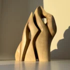 Front view of Together as One hand carved walnut wood sculpture illuminated by warm natural sunlight.