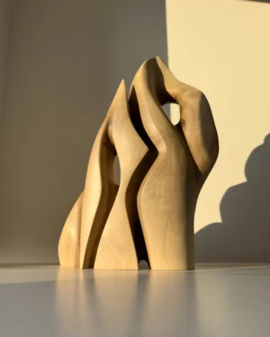 Front view of Together as One hand carved walnut wood sculpture illuminated by warm natural sunlight.