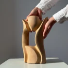 Lumen hand-carved pear wood sculpture shown in hand, revealing its flowing organic form and scale.