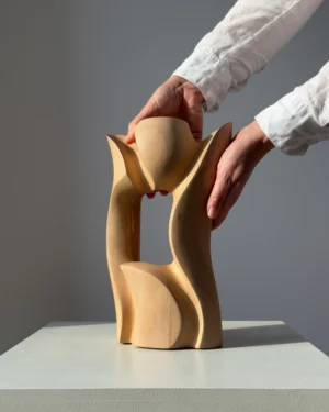 Lumen hand-carved pear wood sculpture shown in hand, revealing its flowing organic form and scale.