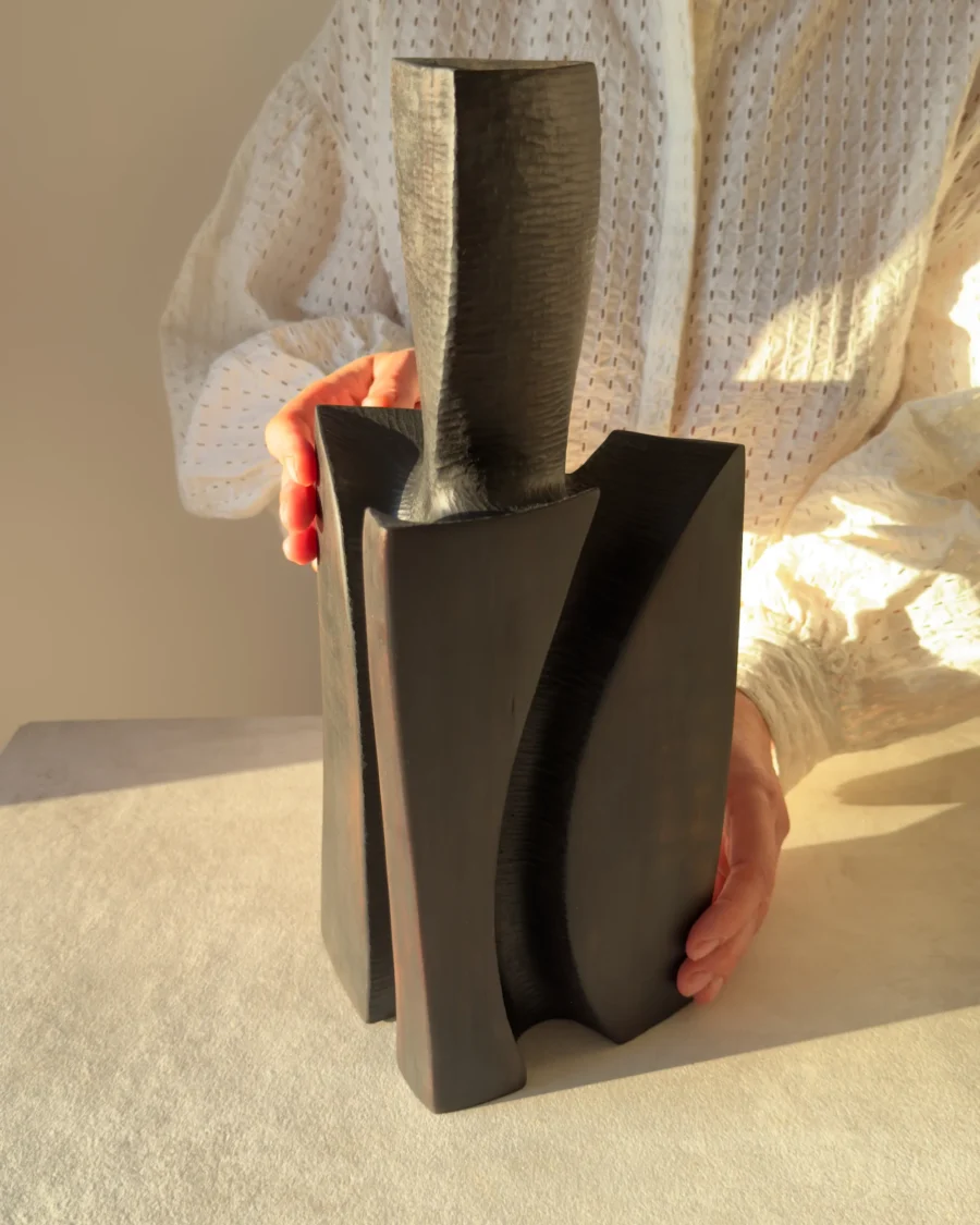 Counterpoise sculptural wooden vase held by the artist, showing its scale, curved supporting forms and hand-carved surface texture.