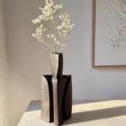 Counterpoise modern sculptural wood vase displayed with delicate white flowers in a minimalist interior and natural side light.