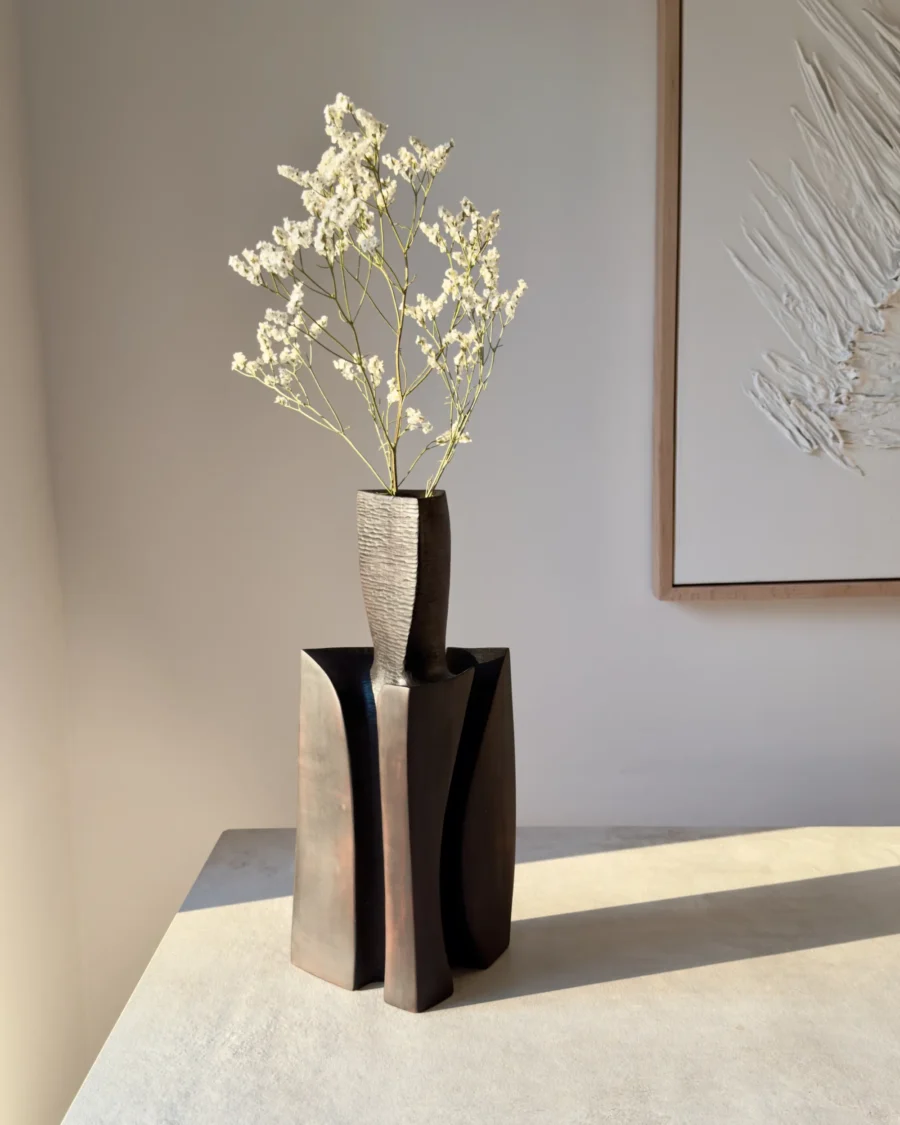 Counterpoise modern sculptural wood vase displayed with delicate white flowers in a minimalist interior and natural side light.