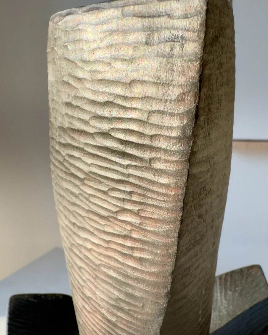 Macro detail of the hand-carved pear wood surface on Counterpoise, with irregular tool marks revealed by natural light.