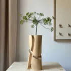 Knot one-of-a-kind hand-carved walnut wood vase displayed with a single dill flower in natural light.