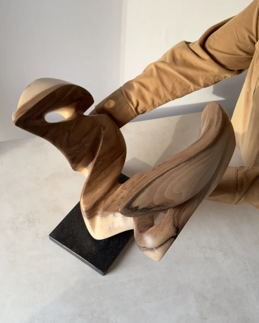 becoming-hand-carved-sculpture-top-view View from above of Becoming held by the artist, revealing the depth between its carved walnut forms and the sculpture’s complex three-dimensional structure.