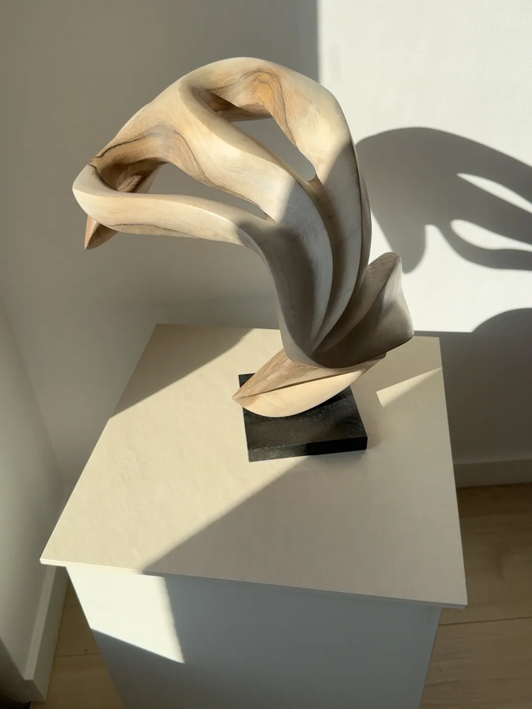 Vertical orientation of Becoming seen from an open side, showing the carved negative spaces and flowing walnut structure.