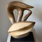 becoming-walnut-sculpture-light-dark-contrast Close view of Becoming held by the artist, showing smooth hand-carved openings, flowing grain and pale walnut surfaces shaped around empty space.