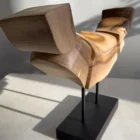 Dynamic Contours one-of-a-kind abstract walnut sculpture with a horizontal carved form raised on steel supports above a black base.