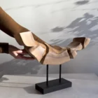 Dynamic Contours hand-carved walnut sculpture shown with the artist’s hands for scale, suspended above a black wooden base.
