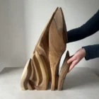 Flowing Unity walnut wood sculpture held by the artist, showing its scale and organic form
