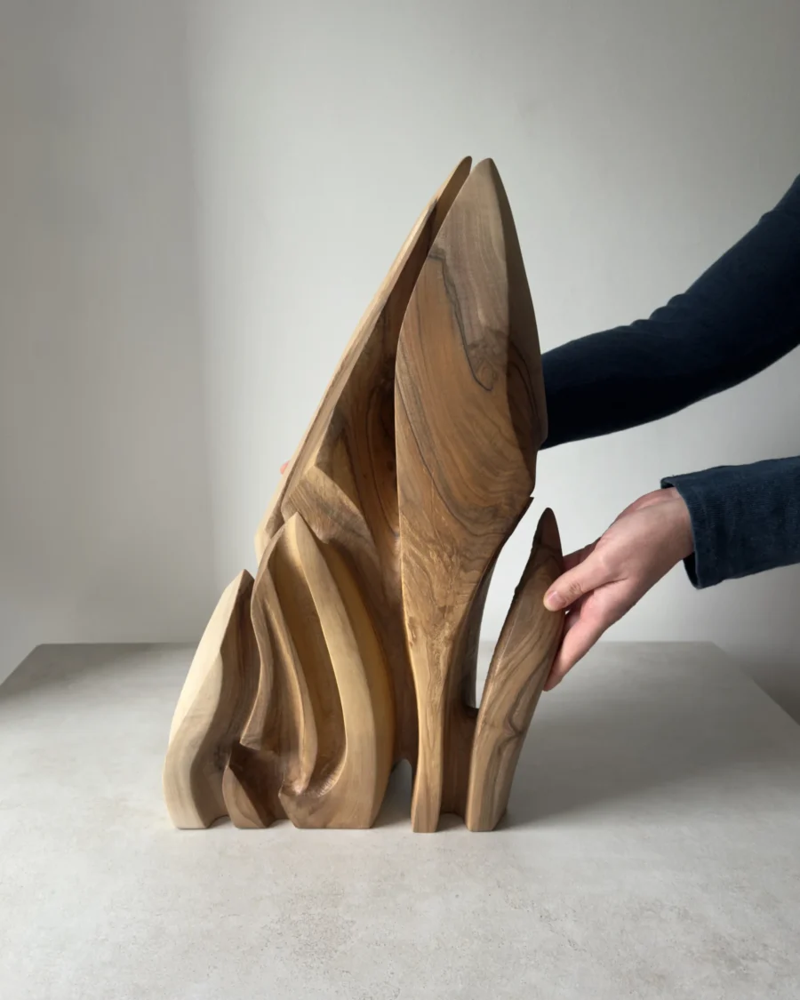 Flowing Unity walnut wood sculpture held by the artist, showing its scale and organic form