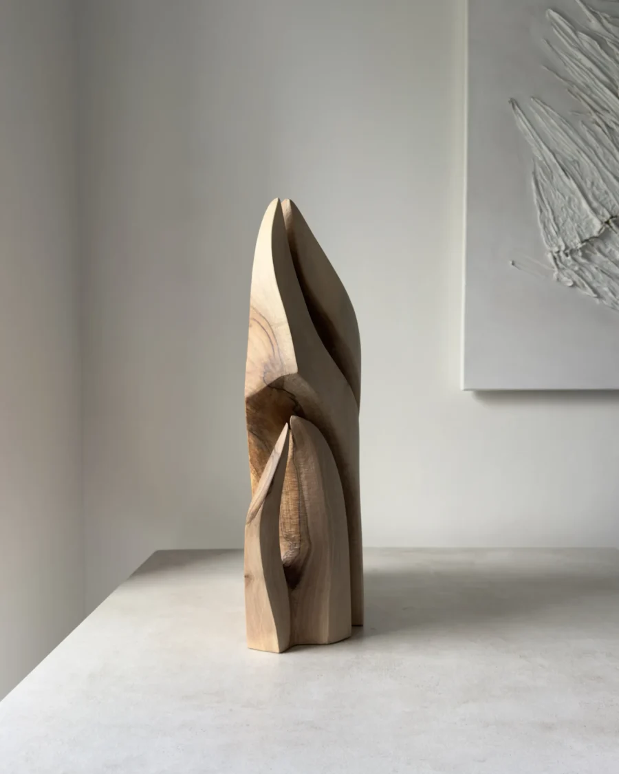 Side view of Flowing Unity showing the layered hand-carved forms and natural walnut grain