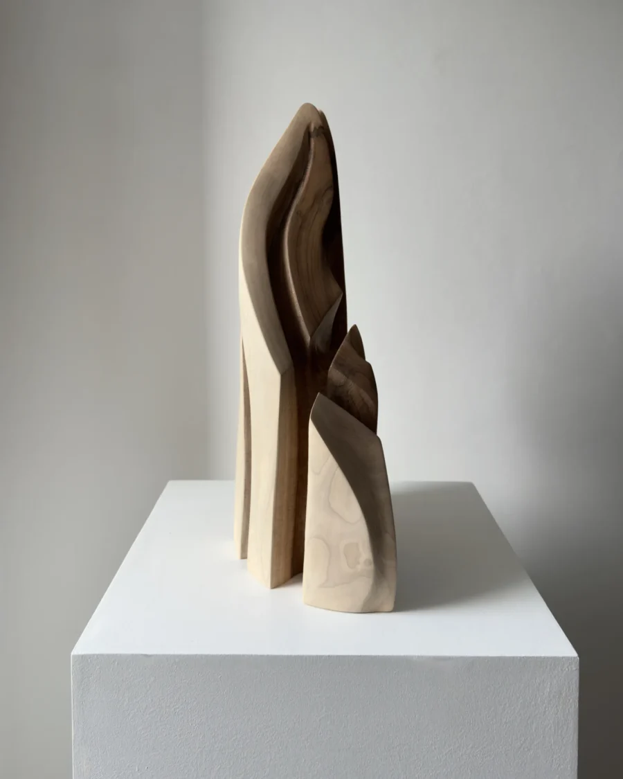 Side view of Flowing Unity showing the slender profile of the hand-carved walnut sculpture