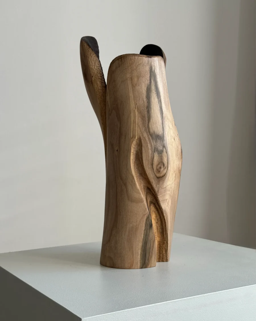 Side view of Hollow contemporary walnut sculpture showing its tall asymmetric silhouette and narrow dark opening.