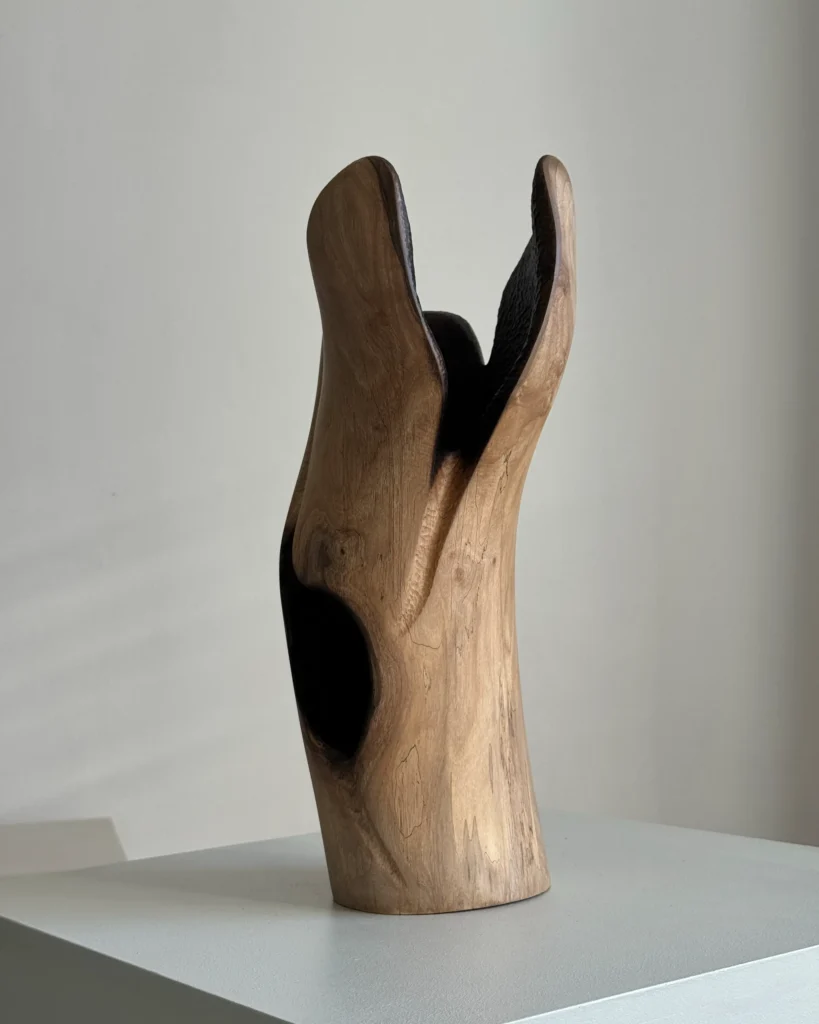 Rear view of Hollow walnut wood vase highlighting the uninterrupted natural grain and softly curved carved surface.