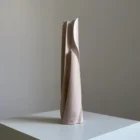 Side view of Hush showing the tall tapered form, flowing carved line and softly white-waxed apple wood surface.