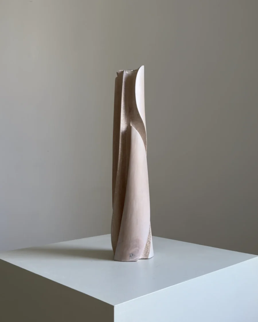 Side view of Hush showing the tall tapered form, flowing carved line and softly white-waxed apple wood surface.