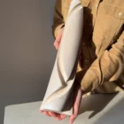 Hush held in the artist's hands to show the scale of the tall, slender hand-carved apple wood sculptural vase.