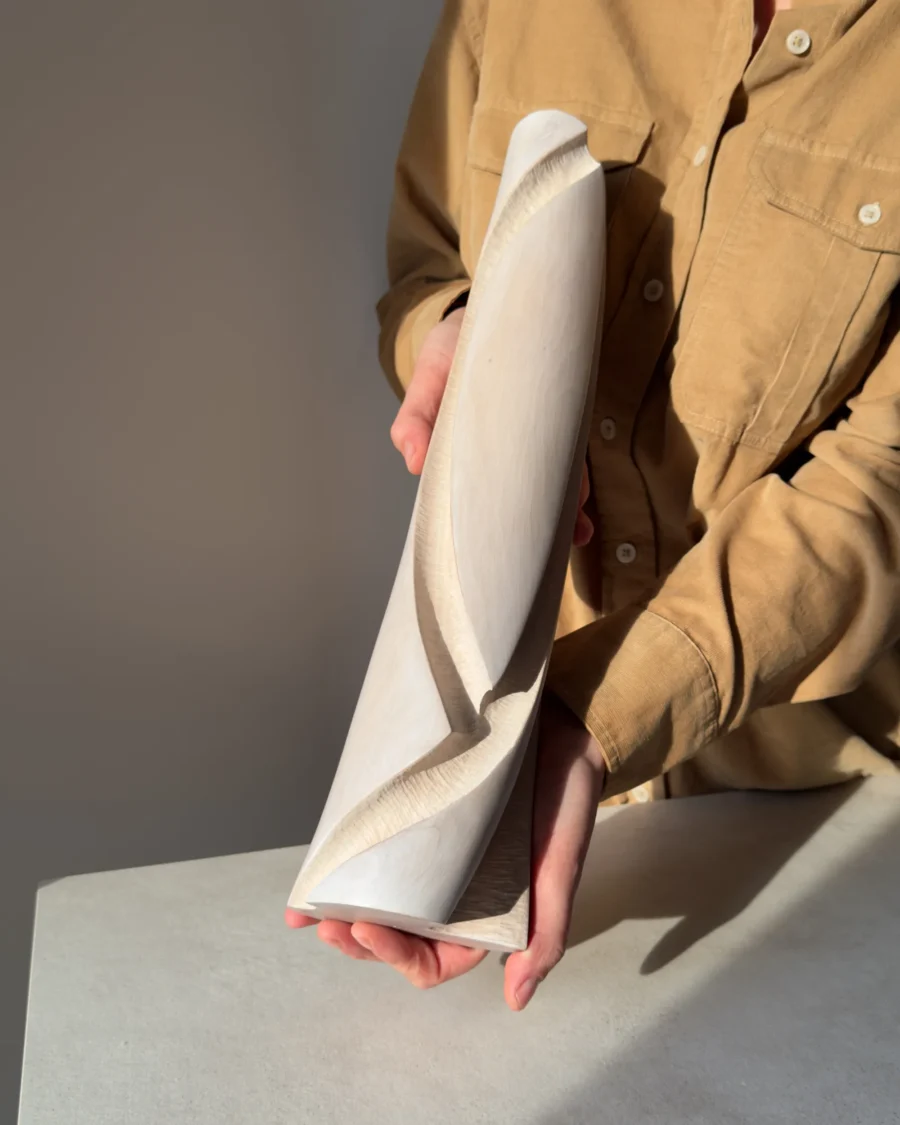 Hush held in the artist's hands to show the scale of the tall, slender hand-carved apple wood sculptural vase.