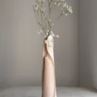 Hush hand-carved wood vase holding a delicate white flowering branch in its removable glass tube.