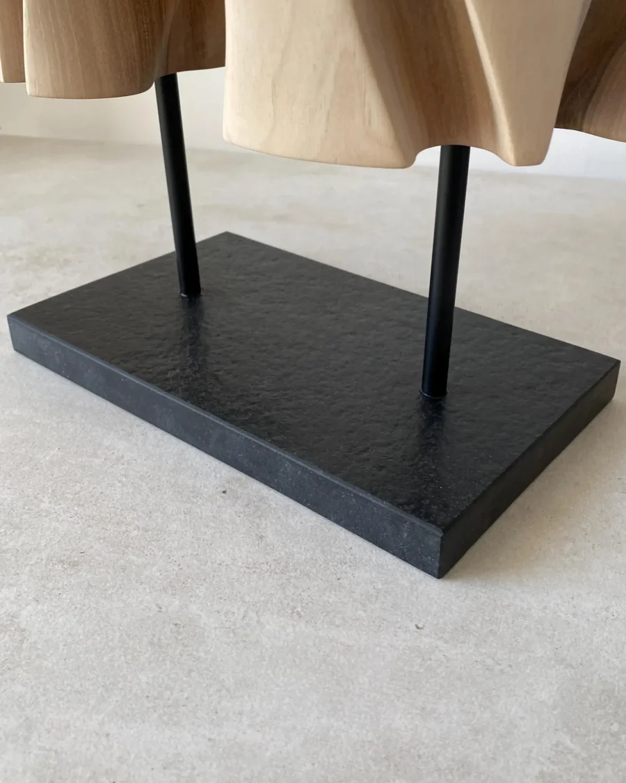 Detail of the black granite base and metal supports beneath Interstice wood sculpture