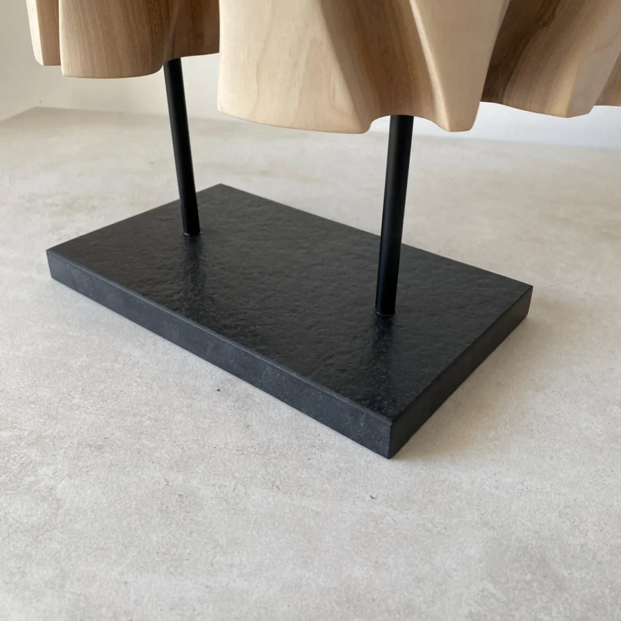 Detail of the black granite base and metal supports beneath Interstice wood sculpture