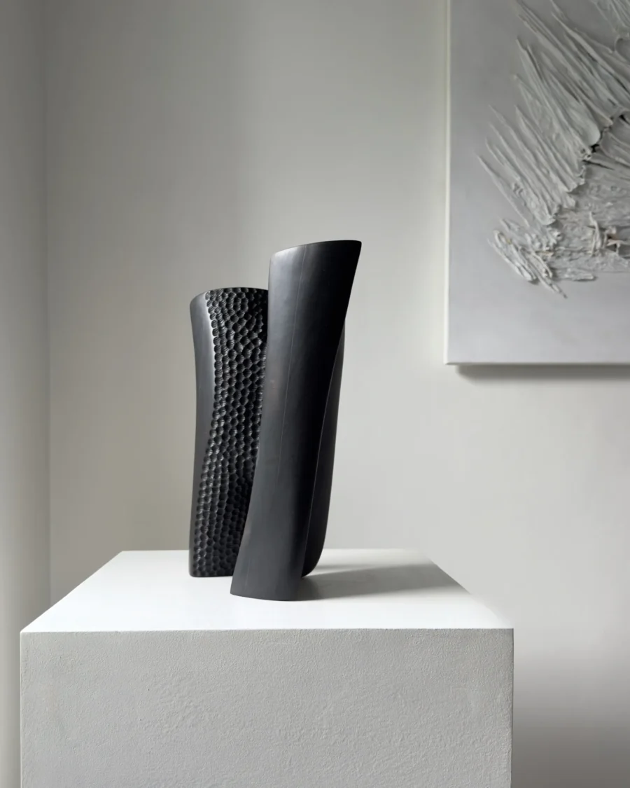 Profile view of Pendere abstract pear wood sculpture, where smooth charred planes partially conceal the textured interior.