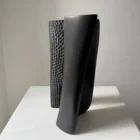Side view of Pendere abstract black pear wood sculpture, with curved charred forms and a textured inner surface in natural light.