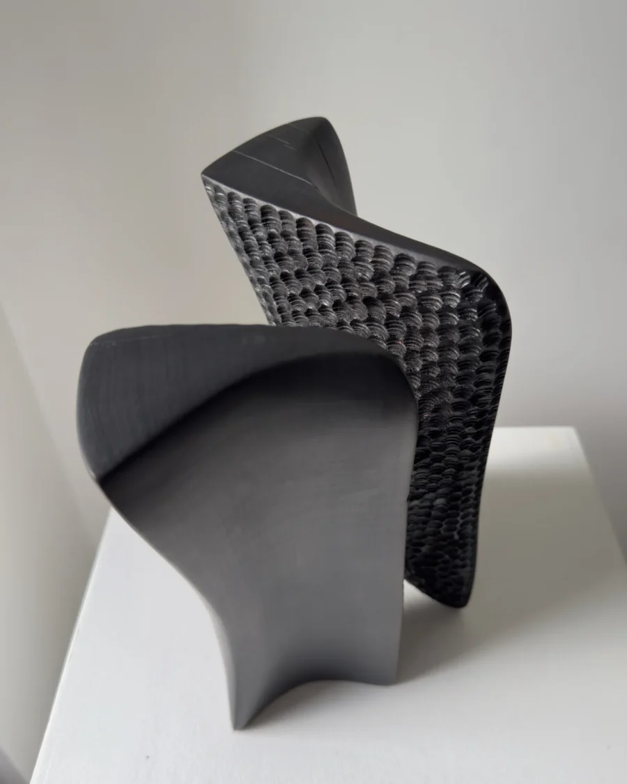 Top view of Pendere revealing its open central passage, curved black surfaces and hand-carved texture in charred pear wood.
