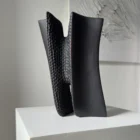 Pendere charred pear wood sculpture in its leaning position, showing smooth black surfaces contrasted with deep hand-carved texture.