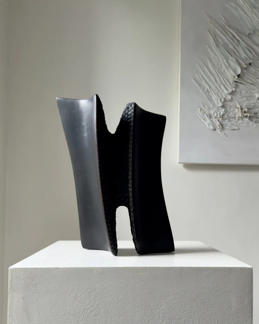 Front view of Pendere showing two rising charred pear wood forms connected through a deeply hand-textured central passage.