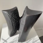 Pendere pear wood sculpture viewed at an angle, revealing the contrast between smooth charred surfaces and its carved textured interior.