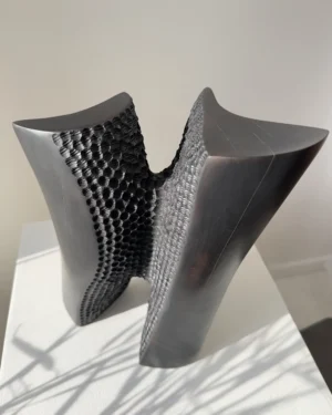Pendere pear wood sculpture viewed at an angle, revealing the contrast between smooth charred surfaces and its carved textured interior.