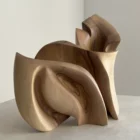 Front angle of Unfurl in soft natural light, showing the broad curved foreground form and layered walnut structure behind it.