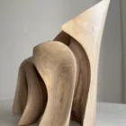 Side and rear view of Unfurl walnut sculpture highlighting the vertical grain, carved depth and curved open structure.