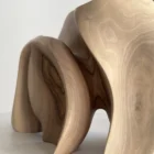 Close-up detail of Unfurl showing the natural walnut grain, smooth hand-finished surface and carved transitions between flowing forms.